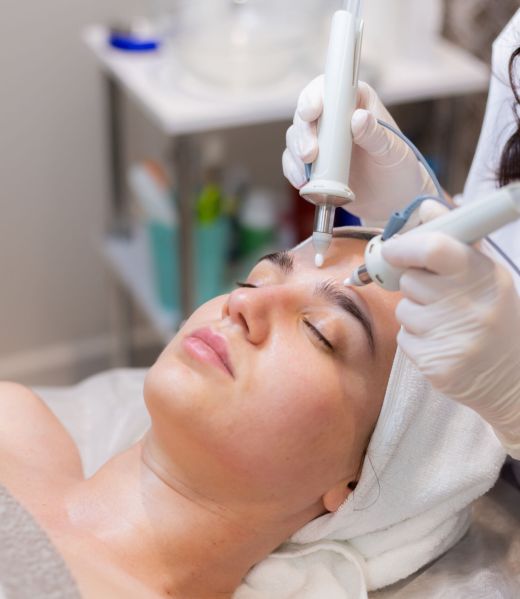 A young beautiful girl lies on the beautician's table and receives procedures with a professional apparatus for skin rejuvenation and moisturizing